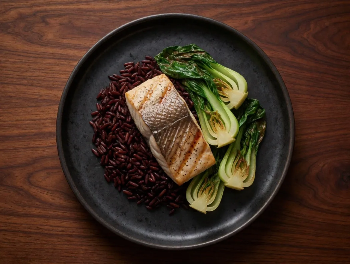 Balanced meal plate with lean protein, complex carbohydrates, and vegetables on a dark surface